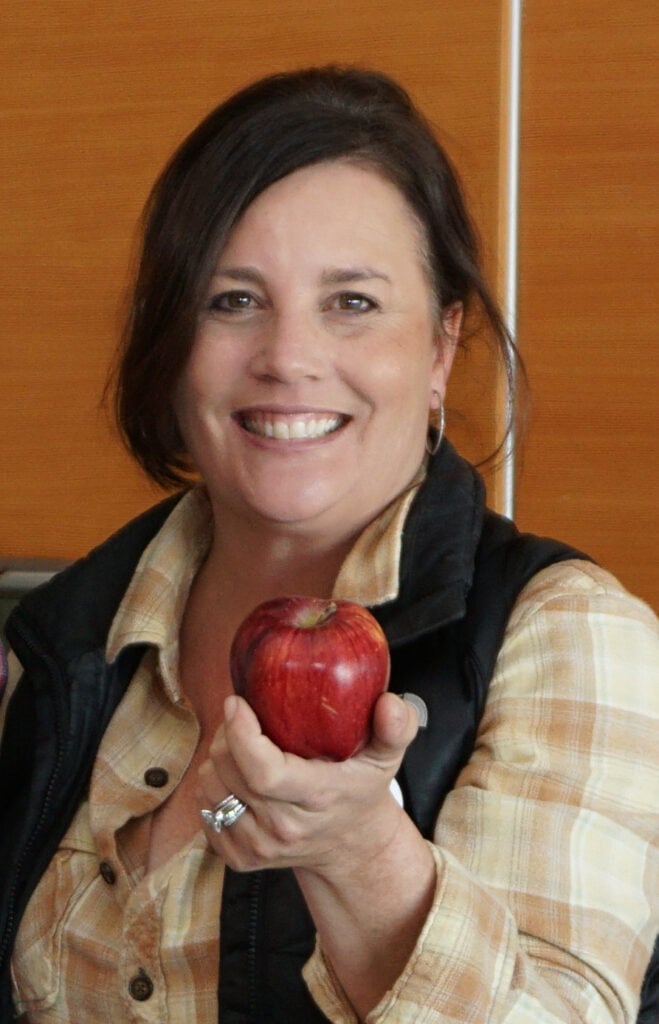 Woman smiling and holding an apple.